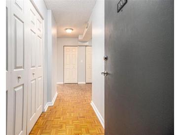 View of hallway with wooden floors, white doors and grey walls leading to the front door at 620 Peachtree Ne St # 1001, Atlanta, GA 30308