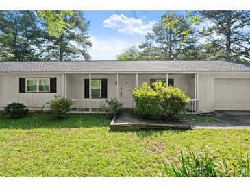 Charming one-story home with a covered front porch and well-maintained landscaping in a lush, green lawn at 1799 Harmony Rd, Powder Springs, GA 30127