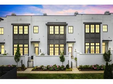 Inviting townhouse showcases a white brick facade, complemented by elegant gray window frames and manicured landscaping at 6640 Avis Walk, Alpharetta, GA 30005