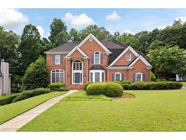 Beautiful two-story brick home featuring a well-manicured lawn and mature landscaping at 2613 Winterthur Main Nw, Kennesaw, GA 30144