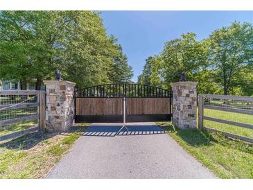 View of the gated entrance to the property, featuring stone pillars and a black metal gate at 664 Johnson Rd, Oxford, GA 30054