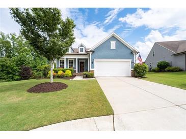 Charming blue home featuring a manicured lawn, colorful shrubs, and a classic two-car garage at 7430 Ramsgate Ct, Cumming, GA 30040