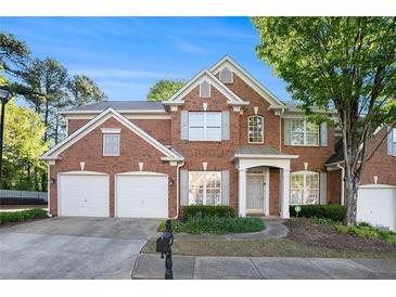 Traditional brick home featuring a two-car garage, gray shutters, and manicured landscaping at 401 Wellwood Way, Roswell, GA 30075
