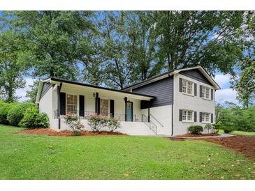 Charming two-story home featuring a manicured lawn, fresh white paint, and contrasting black trim at 2702 Galaxy Ct, Decatur, GA 30034