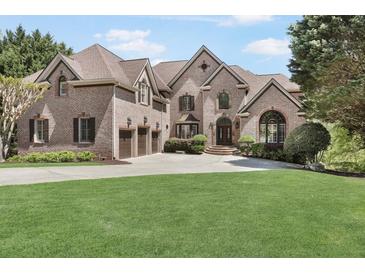 Impressive brick home featuring a lush lawn, three-car garage, and a welcoming entrance with beautiful landscaping at 560 Brook Manor Dr, Johns Creek, GA 30022