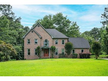 Charming two-story brick home with a well-manicured lawn and mature trees at 13789 Woolsey Rd, Hampton, GA 30228