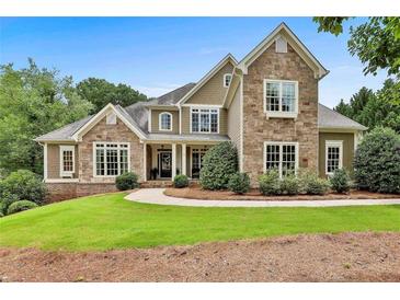 Stunning two-story home with stone and siding exterior, complemented by a lush, manicured lawn at 245 Maple Shade Dr, Tyrone, GA 30290