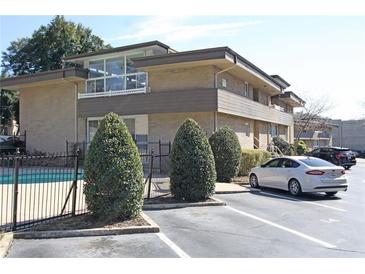Well-maintained building exterior featuring a pool, parking area, and manicured landscaping at 346 Carpenter Drive Northeast Dr # 32, Sandy Springs, GA 30328