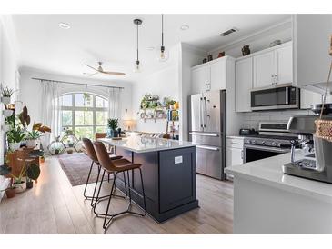 Bright kitchen with stainless appliances, a center island with bar stools, and view into the living space at 625 Piedmont Ne Ave # 3029, Atlanta, GA 30308