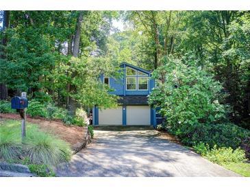 Charming blue home featuring a two-car garage surrounded by lush greenery and a well-manicured lawn at 3531 Evans Ridge Dr, Atlanta, GA 30341