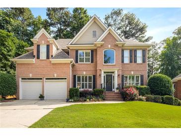 Beautiful two-story brick home with a well-manicured lawn, flowering shrubs, and a two-car garage at 6211 Traymore Se Trce, Smyrna, GA 30082