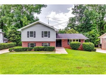 Charming home featuring a well-manicured lawn, a mix of brick and gray siding, and mature trees at 3755 Greentree Dr, Decatur, GA 30032