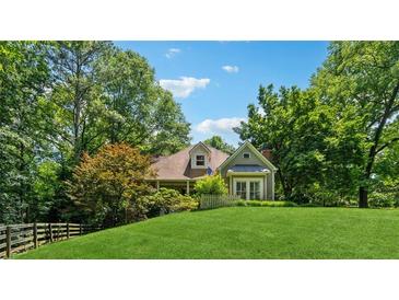 Charming home with a lush green lawn, mature trees, and a quaint picket fence at 1042 Bailey Rd, Woodstock, GA 30188
