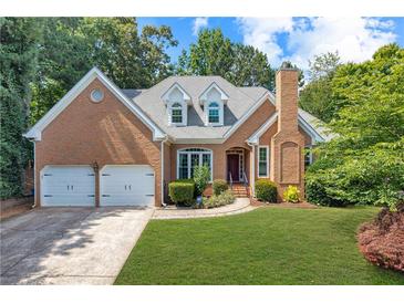 Charming brick home featuring a two-car garage, well-manicured lawn, and classic architectural details at 10880 Windham Way, Alpharetta, GA 30022