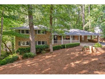Charming brick home with covered porch, carport, and beautifully landscaped front yard with mature trees at 620 Amberidge Trl, Atlanta, GA 30328
