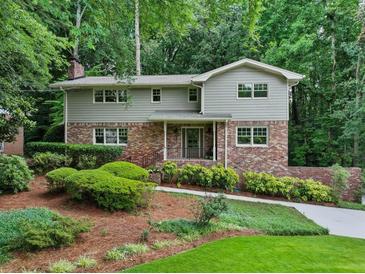 Charming home with a landscaped front yard, brick accents, and surrounded by lush greenery and mature trees at 2973 Payton Ne Rd, Atlanta, GA 30345