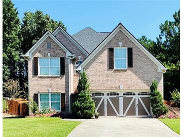Charming two-story brick home with a well-manicured lawn, two-car garage, and meticulous landscaping at 3560 Elinburg Dr, Buford, GA 30519