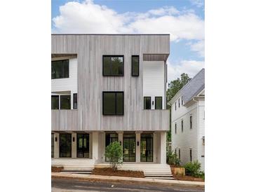Modern townhouse showcasing striking wood siding, sleek black windows, and inviting glass-panel doors at 11560 Serenbe Ln, Chattahoochee Hills, GA 30268