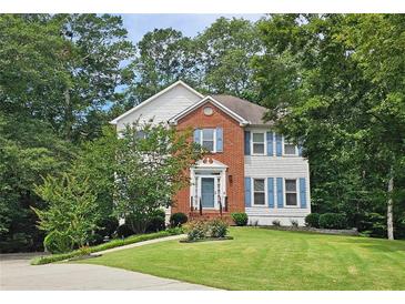 Charming two-story home featuring a well-manicured lawn, brick facade, blue shutters, and lush landscaping at 3152 Andora Sw Trl, Marietta, GA 30064