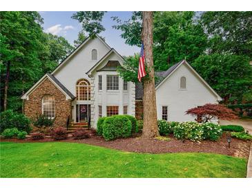 Charming two-story home featuring a stone facade, white siding and a well-manicured lawn at 525 Avala Ct, Johns Creek, GA 30022
