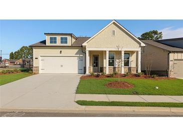 Charming single-story home boasts a manicured lawn, covered porch with columns, and an attached two-car garage at 1693 Juniper Berry Way, Loganville, GA 30052