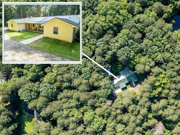 Aerial view of wooded lot featuring yellow home with metal roof at 5357 Highway 81, Loganville, GA 30052