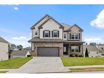 Beautiful two-story home featuring a brick and gray siding exterior with an attached two-car garage and a well-maintained lawn at 1494 Weeping Tree Cir, Auburn, GA 30548