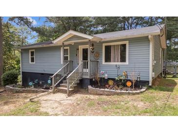Charming blue-sided one-story home featuring a welcoming front porch and beautiful, landscaped flower beds at 5143 3Rd St, Morrow, GA 30260