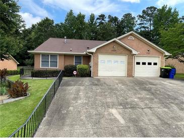 Charming single-story home with a two-car garage and a well-maintained front yard and long concrete driveway at 7123 Woodridge Ln, Union City, GA 30291