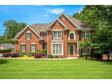 Beautiful two-story brick home with a lush green lawn, manicured landscaping and attractive curb appeal at 4075 Hickory Fairway Dr, Woodstock, GA 30188