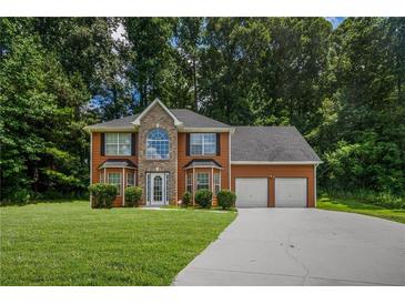 Two-story home with a brick and siding exterior, a two-car garage, and a well-manicured lawn at 5380 Rock Place Drive, Stone Mountain, GA 30087
