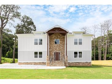 Two-story home with a stone facade, light gray exterior, covered entrance, and landscaped front yard at 2369 Mcafee Rd, Decatur, GA 30032