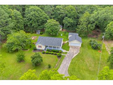 Aerial view of a quaint home with a detached garage, a gazebo, and a long driveway surrounded by lush greenery at 3100 Meadow Trl, Loganville, GA 30052