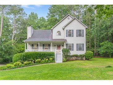 Charming two-story home with grey siding, shutters, a cozy front porch, and lush landscaping at 5609 Twin Oak Dr, Douglasville, GA 30135