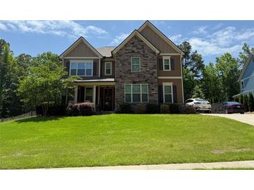 Charming two-story home boasts a stone and siding facade, complemented by a lush green lawn and well-manicured landscaping at 8340 Nolandwood Ln, Villa Rica, GA 30180