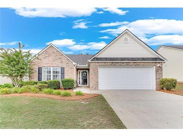 Charming single-story home with a well-manicured lawn, brick facade, and two-car garage at 936 Village View Cir, Loganville, GA 30052