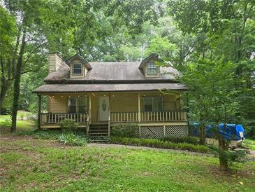 Charming two-story home with a covered front porch, landscaped yard, and mature trees providing shade at 33 Powder Dr, Dallas, GA 30157
