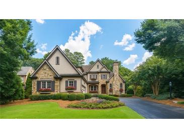 Charming stone and siding home with lush landscaping and a circular driveway at 145 Ardsley Ln, Alpharetta, GA 30005
