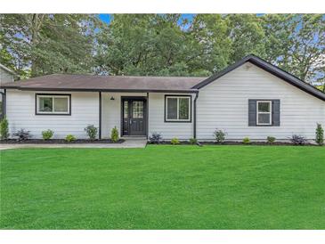 Charming single-story home with a lush green lawn, white siding, black trim, and neatly manicured landscaping at 373 Hemlock Dr, Lawrenceville, GA 30046