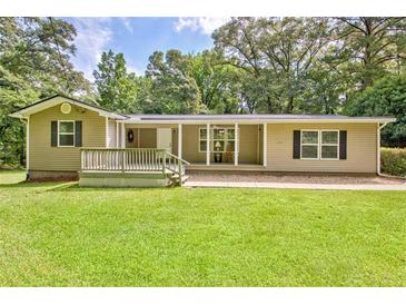 Charming ranch-style home with a welcoming front porch, lush green lawn and mature trees at 3440 Wilson Rd, South Fulton, GA 30349