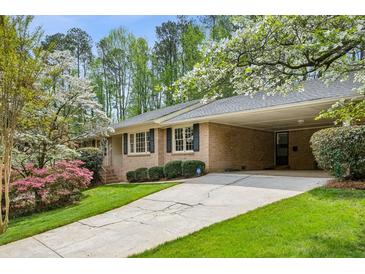 Charming brick home featuring a covered driveway and lush landscaping with flowering trees and shrubs at 3755 Kayanne Ct, Tucker, GA 30084