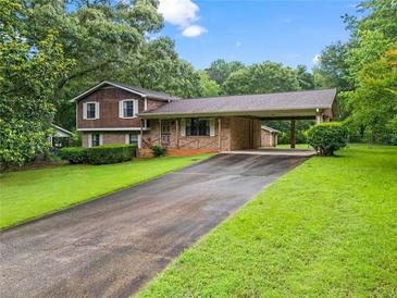 Charming home with a brick facade, wood siding, covered parking, and a spacious front yard at 140 Carriage Cir, Stockbridge, GA 30281