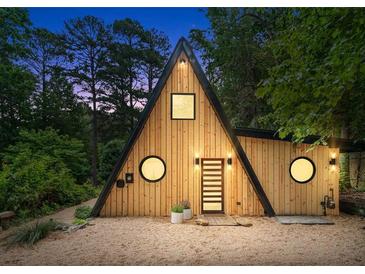 A-frame home featuring natural wood siding, black trim, unique round windows and stylish front door at 3620 Beaver Cove Rd, Cumming, GA 30041