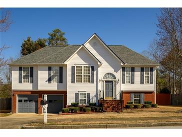 Charming two-story home boasts a brick-accented facade and a well-manicured lawn with mature landscaping at 1305 Bramlett Forest Trail Southeast Trl, Lawrenceville, GA 30045