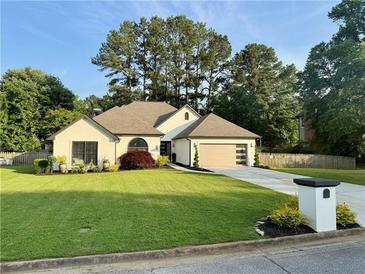 Charming single-story home featuring a manicured lawn, modern garage door, and circular window at 2610 Stokesley Way, Snellville, GA 30078