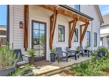 Inviting front porch with seating, brick flooring, and craftsman-style wood beam architectural design creates a welcoming outdoor space at 150 Ray Way, Chattahoochee Hills, GA 30268