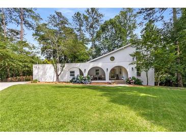 Stunning white home featuring arched front porch, lush lawn, and blooming hydrangea bushes at 5714 Braddock Ct, Atlanta, GA 30350