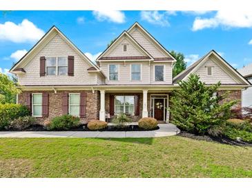 Charming two-story home boasts a manicured lawn, stone accents, symmetrical design, and a welcoming front porch at 1626 Waterchase Dr, Dacula, GA 30019