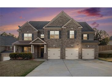 Charming two-story brick home featuring a three-car garage and meticulously manicured lawn at 7691 Brazos Trl, Fairburn, GA 30213