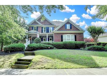 Beautiful two-story brick home with a manicured lawn and a welcoming front porch with beautiful bushes at 4770 Spring Park Cir, Suwanee, GA 30024